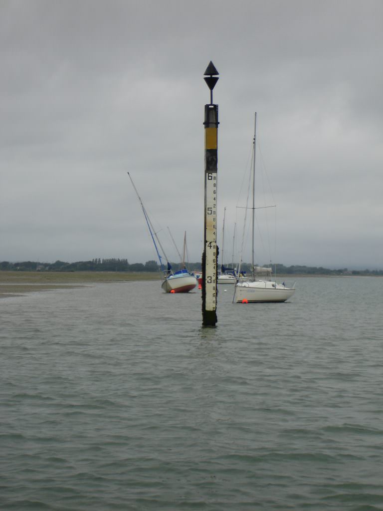 A D53 tidal gauge board set on a post supporting a West Cardinal marker at Hayling Island. The tide is out with all the depth gauge on display