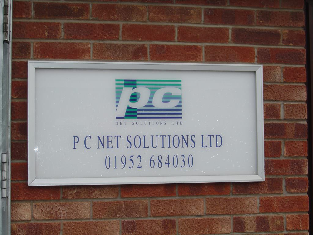 A small wall mounted company entrance sign supplied with an aluminium Pantrim frame.  On a brick wall 