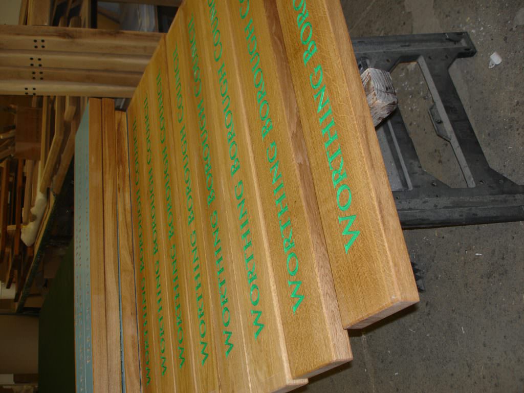An example of routed oak signs in production in our factory.  A batch of signs with indented text painted green
